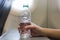 A passenger woman on a airplane flight drinking a bottle of water