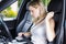 Passenger woman fastening seat belt in car