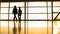 Passengers in front of window in airport, silhouette, warm