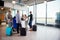 Passengers With Luggage Standing While Receptionists Working At