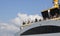 Passengers travel on the ferry. Blue sky in sunny daytime. Buildings built on the left