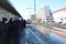 Passengers wait for a tram on rails in a puddle for a ride in a dirty city in the spring in