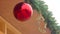 Passers-by reflection in bright Christmas ball hanging under roof of house