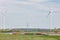 Passing bulk container ship on the Dutch river IJssel in front of a large energy production facility with wind turbines and solar