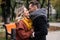 Passionate couple handsome guy hold his girlfriends hands and touching noses stand in fall town park wearing coats and