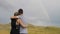 Passionate couple of teen lovers with smartphone taking selfies and photographing the picturesque countryside panorama rainbow -
