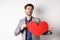 Passionate handsome man showing heart pounding gesture with red valentines cutout, standing in suit and searching for