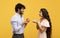 Passionate indian man proposing to his beloved lady, giving her engagement ring on Valentine's Day, yellow background