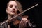 Passionate violin musician playing on black background