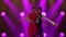 Passionate young couple dancing classic Argentine tango in a dark studio with bright purple lights. Woman in red dress