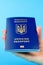 Passport of a citizen of Ukraine in a female hand on a blue background. Inscription in Ukrainian Ukraine Passport