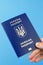 Passport of a citizen of Ukraine in a female hand on a blue background. Inscription in Ukrainian Ukraine Passport