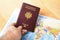 Passport in hand with a world\'s maps on table