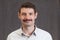 Passport photo of a smiling forties man with a mustache