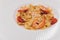 Pasta bavette with fried shrimps, bechamel sauce, mint leaf, garlic, tomatoes, chili on white plate, top view, italian