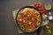 Pasta Bolognese bucatini with mincemeat and tomatoes, dark wooden background, top view, copy space