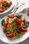 Pasta in carbonara sauce with fried bacon and fresh tomatoes, garnished with dill.  Appetizing hearty portions on the table