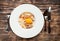 Pasta Carbonara on white plate with parmesan and yolk on dark wooden background