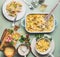 Pasta casserole with romanesco cabbage and ham in creamy sauce, served in plate with cutlery on kitchen table with ingredients, t