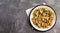 Pasta with cheese and meat with herbs on a round plate on a dark background