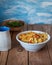 Pasta with chicken meat and pepper in a deep light plate, in the background a bowl with tomatoes and a doll. Poking a