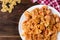 Pasta with chicken, spices and tomato sauce on dark wooden background