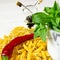 Pasta, chilli, green basil and olive oil on a white wood table