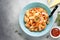 Pasta conchiglioni (conchiglie, shells) with tomato sauce, Parmesan cheese and thyme in a blue plate on a gray background.