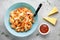 Pasta conchiglioni (conchiglie, shells) with tomato sauce, Parmesan cheese and thyme in a blue plate on a gray background.