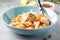 Pasta conchiglioni (conchiglie, shells) with tomato sauce, Parmesan cheese and thyme in a blue plate on a gray background.