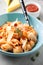 Pasta conchiglioni (conchiglie, shells) with tomato sauce, Parmesan cheese and thyme in a blue plate on a gray background.