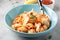 Pasta conchiglioni (conchiglie, shells) with tomato sauce, Parmesan cheese and thyme in a blue plate on a gray background.