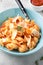 Pasta conchiglioni (conchiglie, shells) with tomato sauce, Parmesan cheese and thyme in a blue plate on a gray background.