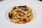 Pasta dish cheese sauce mix with bacon chilli and fresh ingredient serve in white plate background