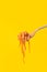 Pasta falling from fork on yellow background.