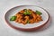 Pasta farfalle with eggplant, tomato sauce, cheese and basil close up