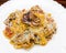 Pasta farfalle with stewed baby octopus and cheese served on white plate. Mediterranean cuisine Healthy diet food concept