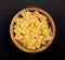 Pasta Farfalle in wooden bowl on black background, top view, centered