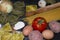 Pasta food background with a copy space of ravioli, spaghetti,egg,potato,tomato and a wood kneader on floury black background