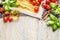 Pasta with fresh tomatoes, basil and olive oil on light shabby rustic background, top view, border.