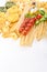 Pasta with fresh tomatoes, basil and olive oil on light shabby rustic background, top view, border. Pasta with