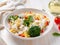 Pasta fusilli with vegetables, boiled steamed meat, white sauce on white wooden table, low-calorie food, low-fat diet, side view