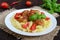 Pasta futsilli with meat balls, cherry tomatoes, basil on a white plate