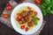 Pasta futsilli with meat balls, cherry tomatoes, basil on a white plate on a dark wooden background.