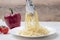 Pasta with gralic and chili. Hand with tongs move spaghetti with butter to a white plate on wood background