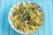 Pasta with grilled turkey, pesto sauce and rosemary in serving plate over wooden turquoise background