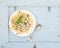 Pasta mafaldine with mushrooms and cream sauce in white ceramic plate over light blue wooden background. Top view.
