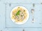 Pasta mafaldine with mushrooms and cream sauce in white ceramic plate over light blue wooden background. Top view.