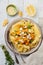 Pasta Mafaldine Napoletane with baked pumpkin, feta cheese and seasoning herbs in ceramic plate on white wooden background.