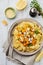 Pasta Mafaldine Napoletane with baked pumpkin, feta cheese and seasoning herbs in ceramic plate on white wooden background.